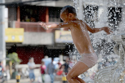 A boy frolics at a fountain to cool off from the summer heat