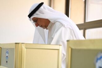 A man fills in his ballot paper at a polling station in Capital Governorate, Kuwait