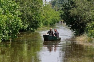 People sail on a boat in a flooded area of the Kherson region
