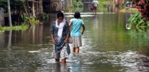 People wade through flood water in flood-hit Bajali district of Assam