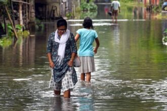 People wade through flood water in flood-hit Bajali district of Assam