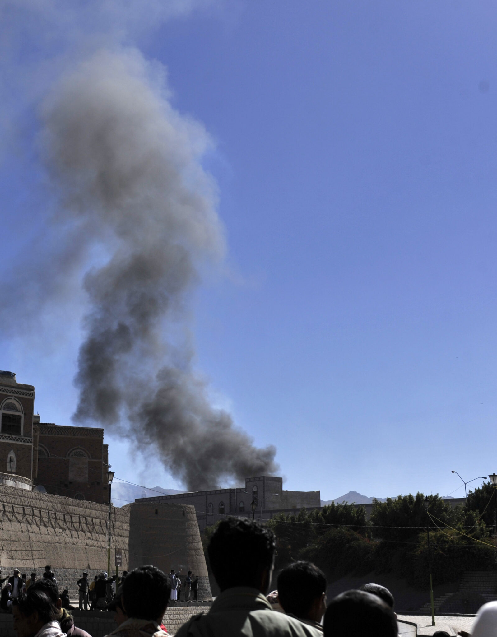 People watch smoke rise from the Defense Ministry in Sanaa
