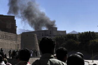 People watch smoke rise from the Defense Ministry in Sanaa