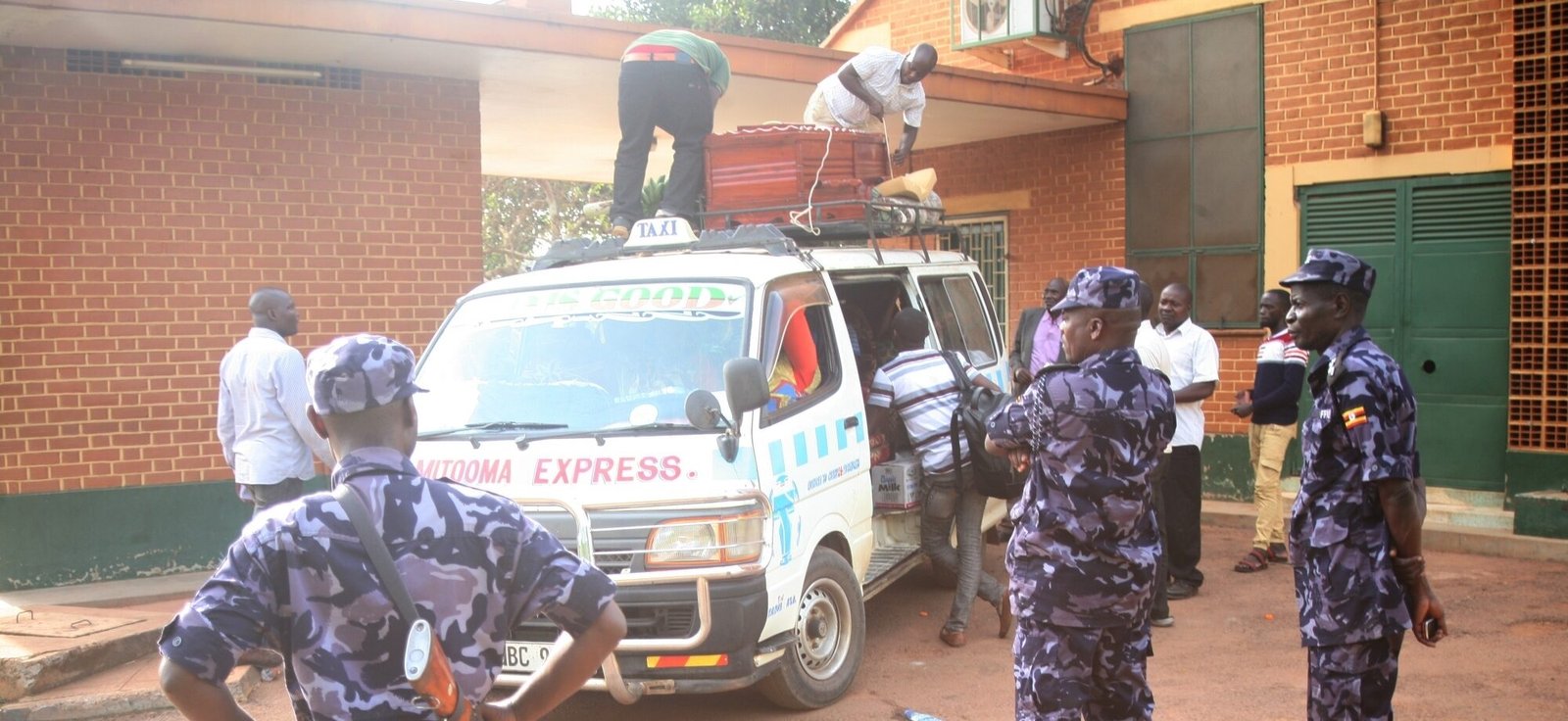 Policemen stand guard as people load a casket of boat accident victim in Kampala