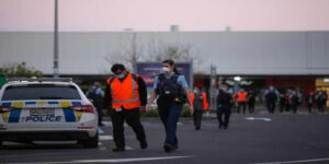 Police officers stand guard near the New Lynn supermarket in Auckland, New Zealand