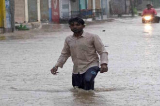 A man walks through a waterlogged road